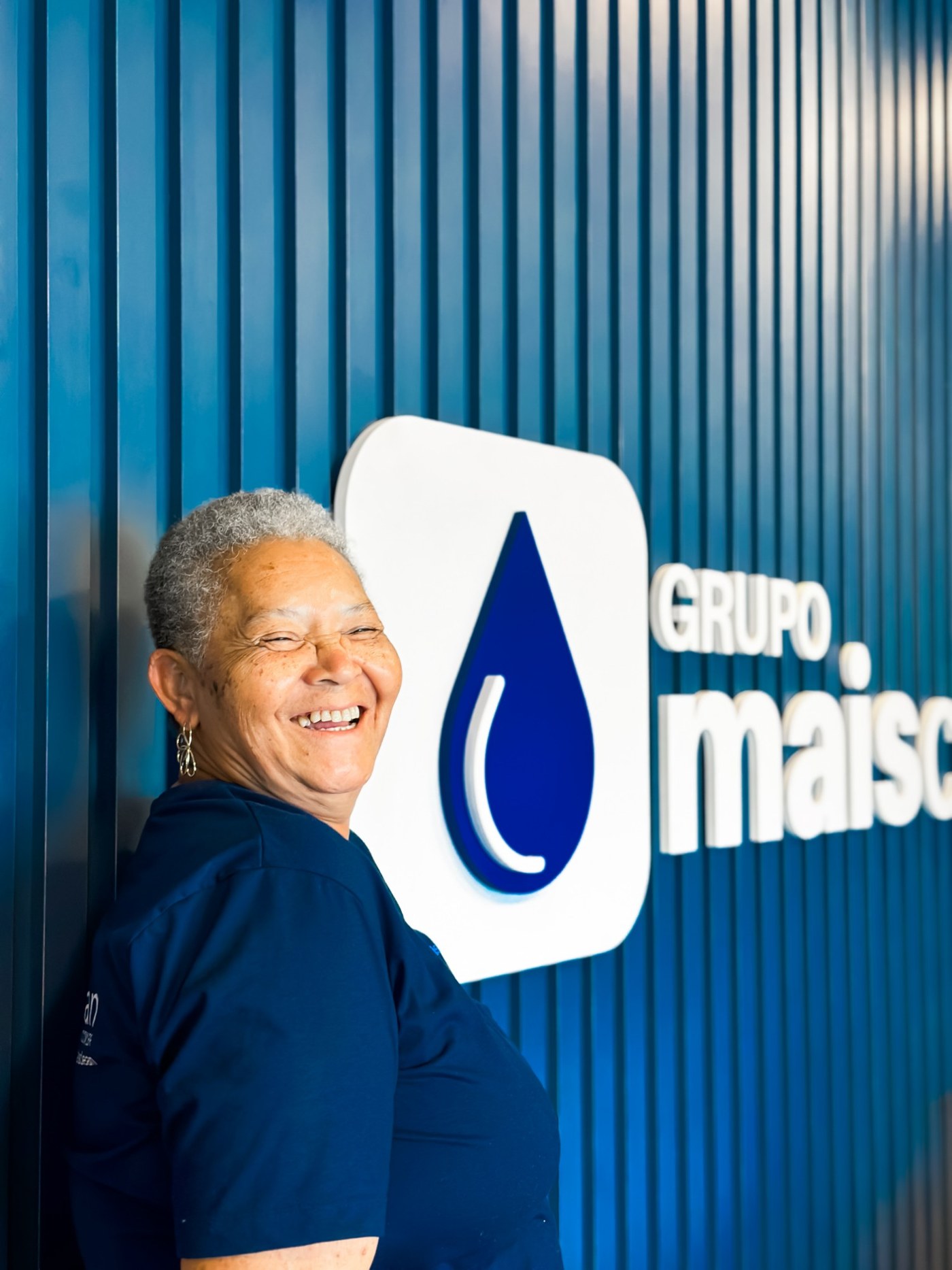Colaboradora sorrindo ao lado da logo do Grupo Mais Clean